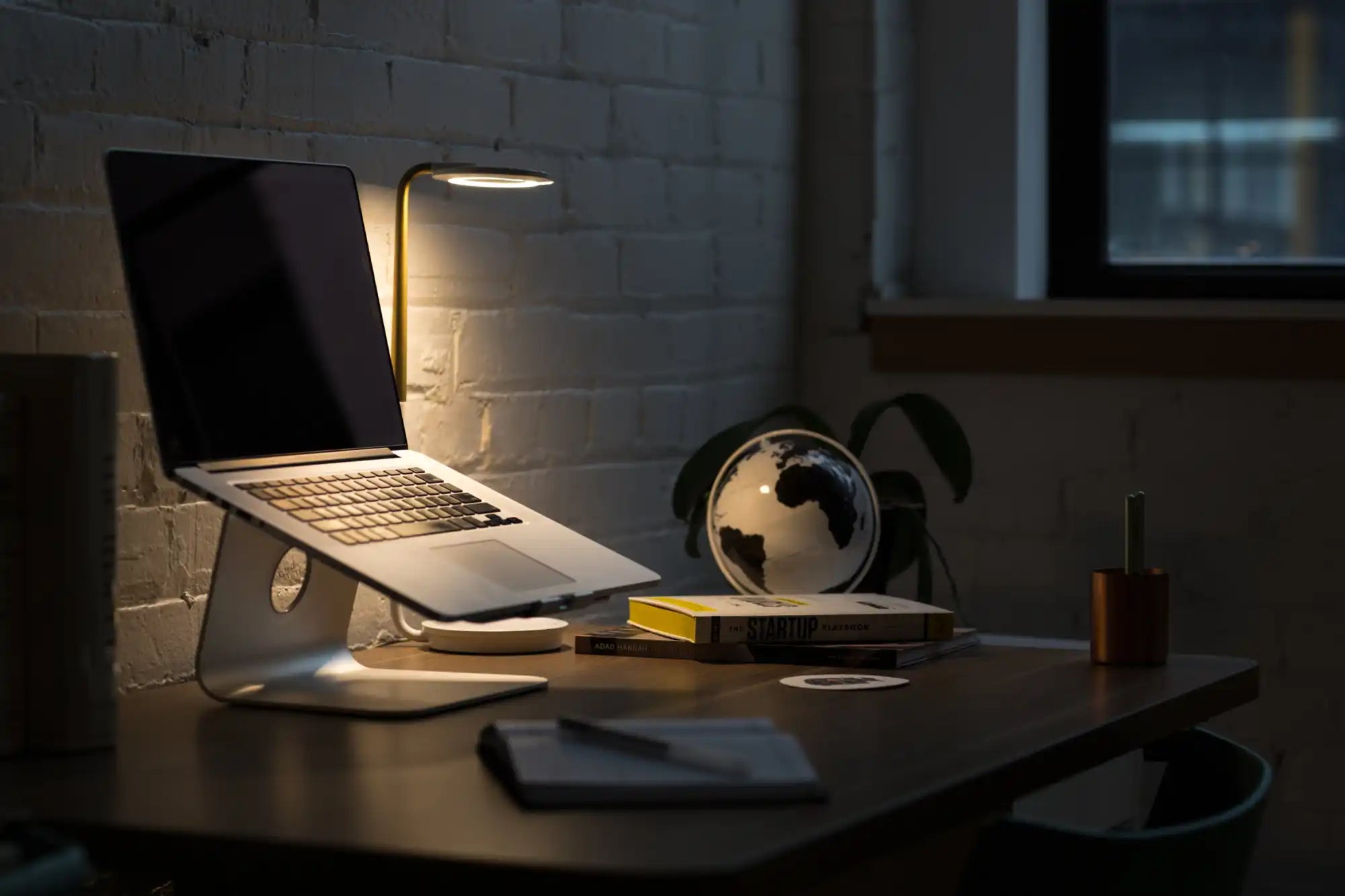 MacBook laptop illuminated by soft lighting on a desk.